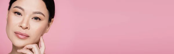 Азиатская женщина с макияжем глядя на камеру изолированы на розовый, баннер — стоковое фото