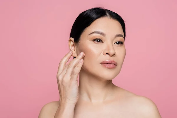 Asian woman with naked shoulders touching face isolated on pink — Stock Photo