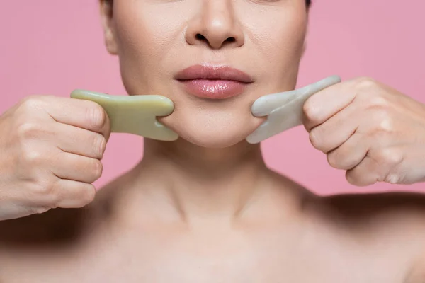 Vista ritagliata della donna massaggiare mento con pietre di giada isolato su rosa — Foto stock