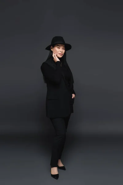 Asiatische Frau mit Fedora-Hut posiert auf dunkelgrauem Hintergrund — Stockfoto