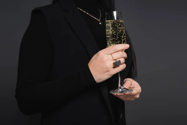 Cropped view of woman in jacket holding glass of champagne isolated on dark grey — Stock Photo