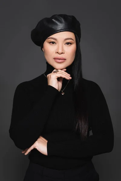 Portrait of stylish asian woman in beret looking at camera isolated on dark grey — Stock Photo