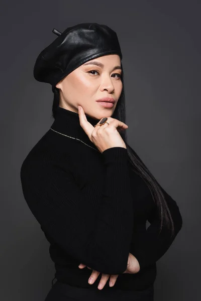 Stylish asian model in beret looking at camera isolated on dark grey — Stock Photo