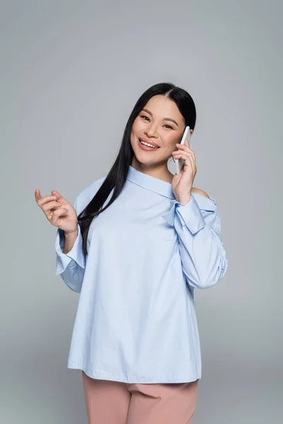 Lächelndes asiatisches Model in Bluse spricht auf Smartphone isoliert auf grau — Stockfoto