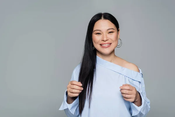 Happy asian model in blouse looking at camera isolated on grey — Stock Photo