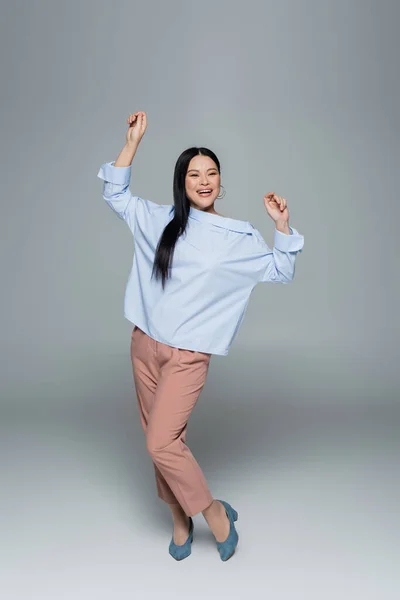 Volle Länge der positiven asiatischen Modell tanzen auf grauem Hintergrund — Stockfoto