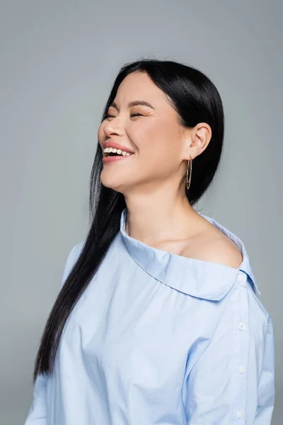 Portrait of asian woman with closed eyes laughing isolated on grey — Stock Photo