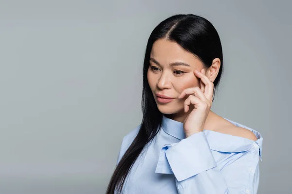 Pensive asian woman in blouse looking away isolated on grey — Stock Photo