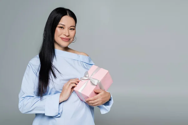 Asian woman in blue blouse holding present isolated on grey — Stock Photo