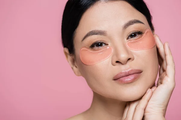 Retrato de mujer asiática con parches oculares de hidrogel aislados en rosa - foto de stock