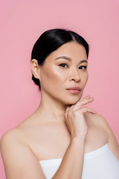 Mulher asiática em top branco posando e olhando para a câmera isolada em rosa — Fotografia de Stock