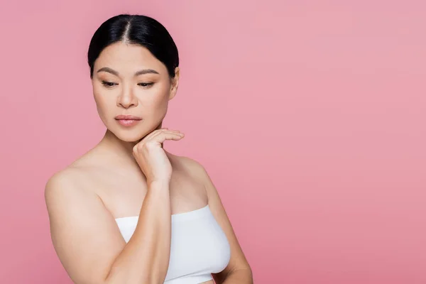 Morena asiática mujer en blanco superior mirando lejos aislado en rosa - foto de stock