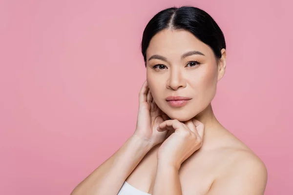 Asian woman with naked shoulder looking at camera isolated on pink — Stock Photo