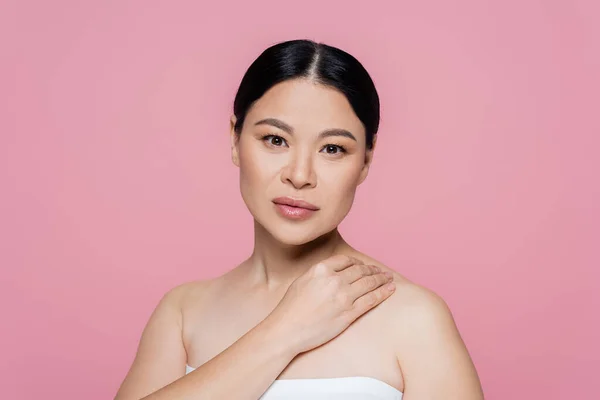 Asian woman in top touching shoulder isolated on pink — Stock Photo