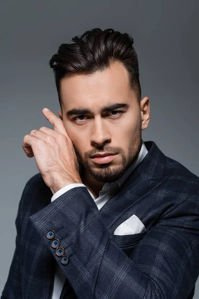 Joven hombre de negocios barbudo en chaqueta a cuadros mirando a la cámara aislada en gris — Stock Photo