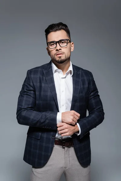 Bearded businessman in blazer and glasses looking at camera isolated on grey — Stock Photo