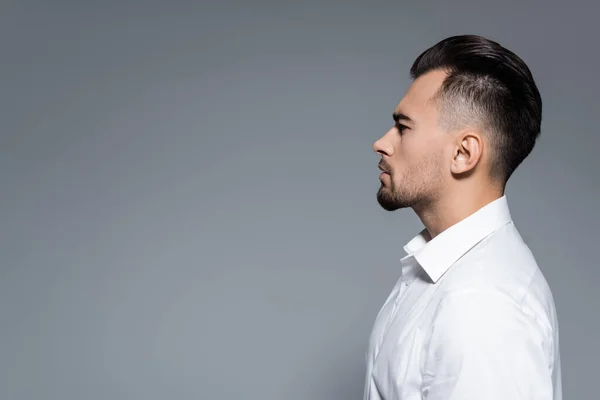 Vista lateral del hombre de negocios barbudo en camisa blanca aislada en gris - foto de stock