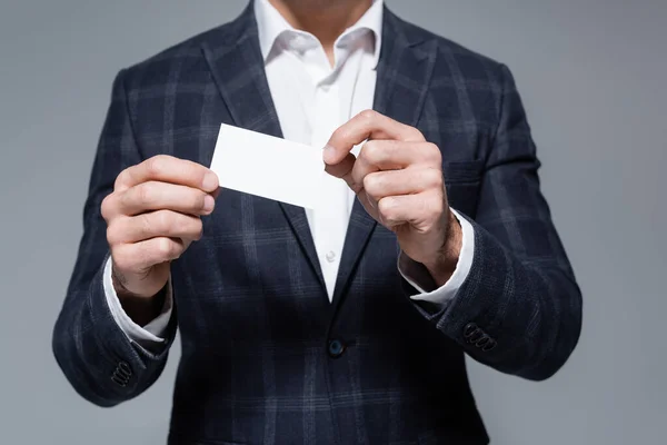 Vista parcial del hombre de negocios en chaqueta a cuadros que sostiene la tarjeta en blanco aislado en gris - foto de stock