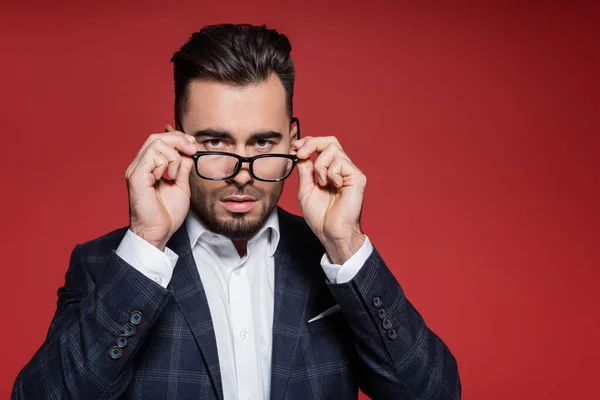 Joven hombre de negocios en chaqueta a cuadros ajustando gafas en rojo — Stock Photo