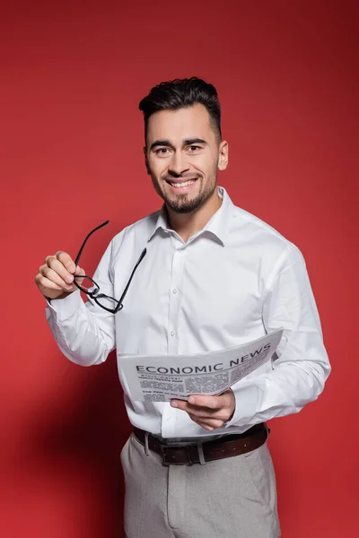 Fröhlicher Geschäftsmann im weißen Hemd mit Brille und Zeitung auf Rot — Stockfoto