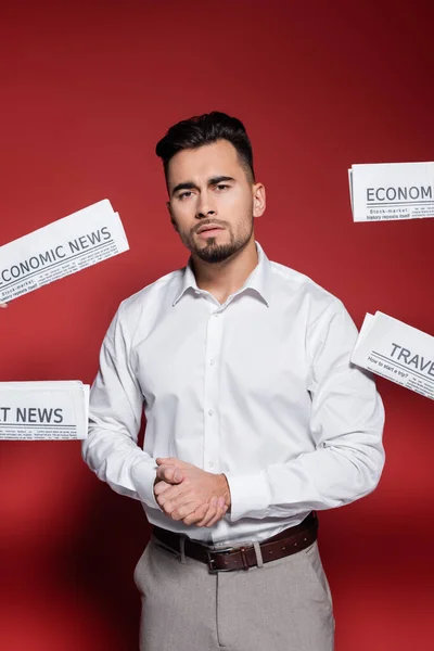Bearded businessman in white shirt near newspapers on red — Stock Photo