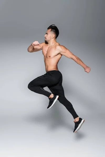 Full length of bearded and muscular sportsman running on grey — Stock Photo