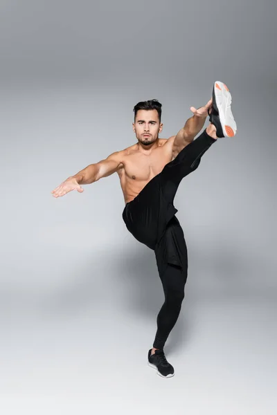 Full length of shirtless sportsman exercising with outstretched hands on grey — Stock Photo