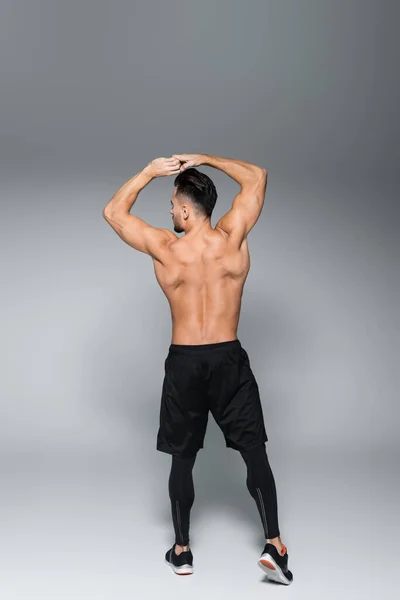 Back view of shirtless and muscular sportsman posing on grey — Stock Photo