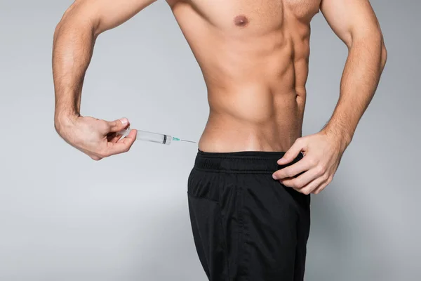 Vista recortada de deportista sin camisa y musculoso inyectándose esteroides en gris - foto de stock