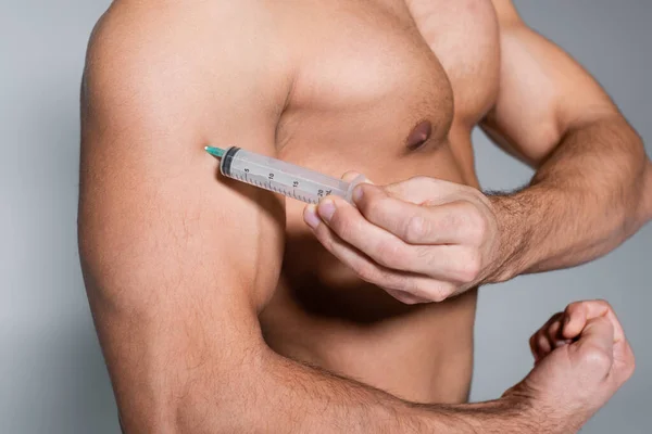 Cropped view of shirtless sportsman injecting himself in muscle isolated on grey — Stock Photo