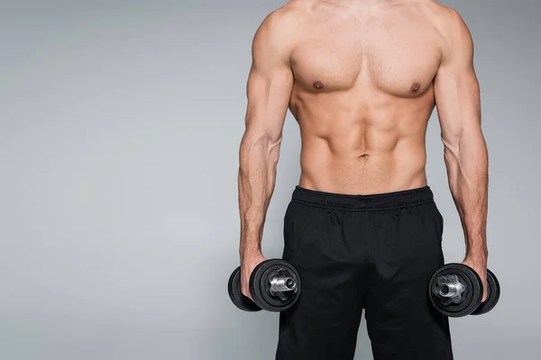 Partial view of strong man training with dumbbells isolated on grey — Stock Photo