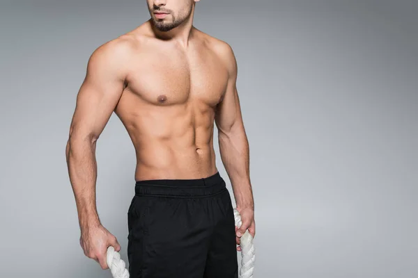 Cropped view of shirtless sportsman holding battle ropes isolated on grey — Stock Photo