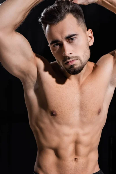 Hemdloser und muskulöser Sportler, der isoliert auf schwarz in die Kamera blickt — Stockfoto
