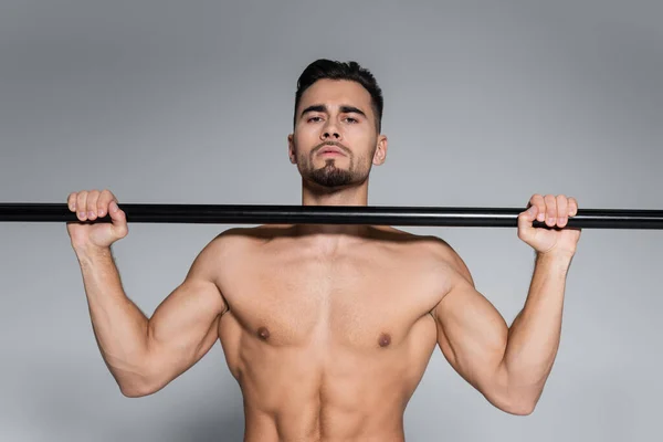 Shirtless sportsman exercising on horizontal bar isolated on grey — Stock Photo