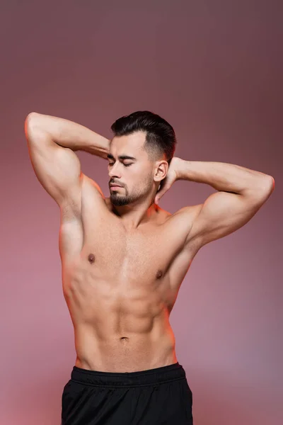 Lighting on shirtless man with muscles posing on pink and grey — Stock Photo