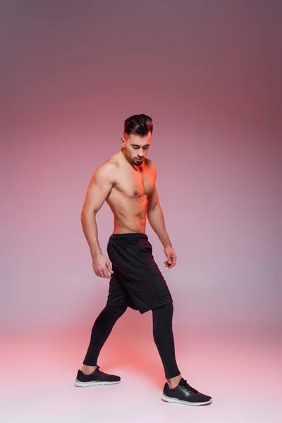 Full length of shirtless sportsman posing on grey and pink — Stock Photo