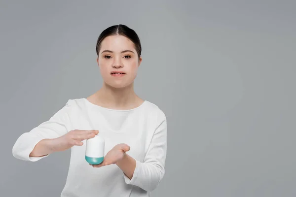 Woman with down syndrome holding deodorant isolated on grey — Stock Photo