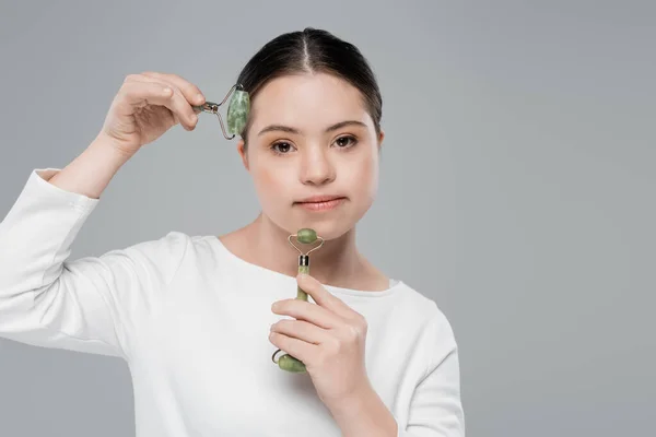 Jovem com síndrome de down usando rolos de jade isolados em cinza — Fotografia de Stock