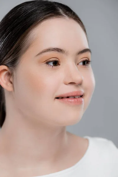 Donna sorridente con sindrome di Down distogliendo lo sguardo isolato sul grigio — Foto stock