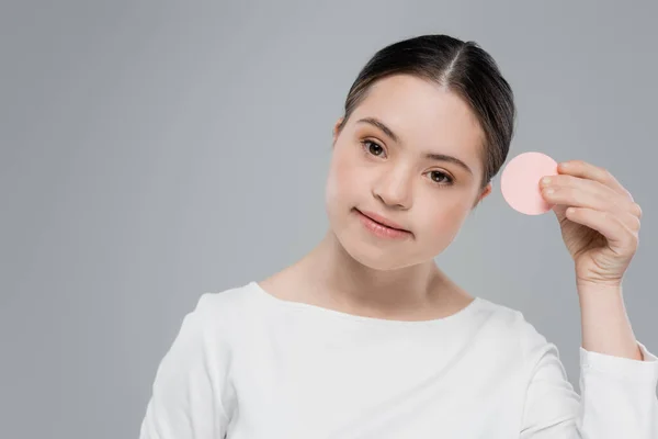 Woman with down syndrome holding sponge and looking at camera isolated on grey — Stock Photo