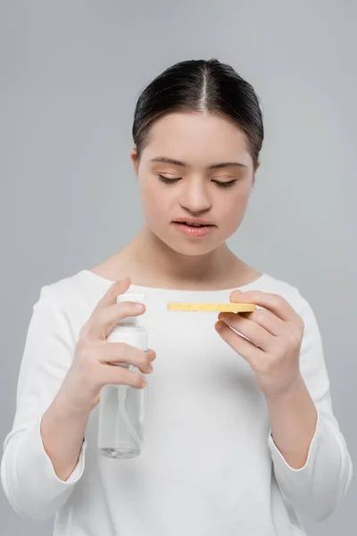 Woman with down syndrome holding sponge and cleansing foam isolated on grey — Stock Photo