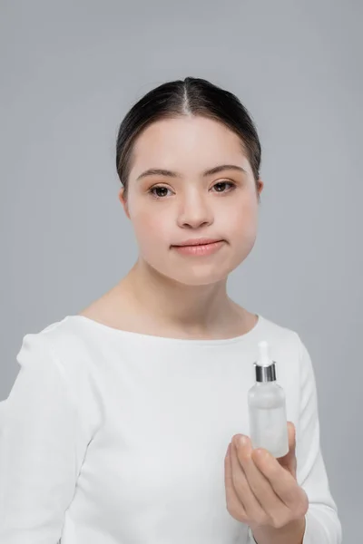 Молодая женщина с синдромом Дауна держит сыворотку, изолированную от серого — стоковое фото