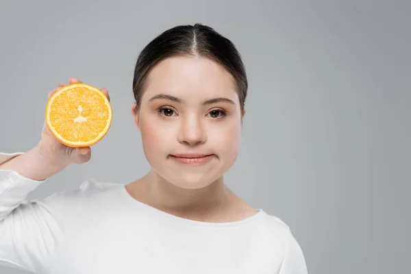 Junge Frau mit Down-Syndrom hält Orange auf Grau isoliert — Stockfoto