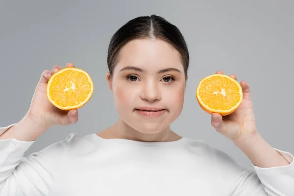Усміхнена жінка з синдромом Дауна тримає апельсин ізольовано на сірому — стокове фото