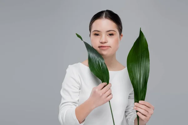 Женщина с синдромом Дауна держит листья изолированы на серый — стоковое фото