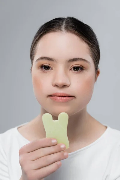 Frau mit Down-Syndrom hält Jadestein isoliert auf grau — Stockfoto