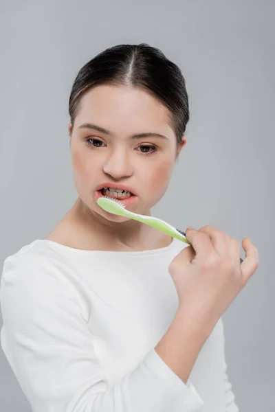 Brunette femme avec le syndrome du duvet brossage des dents isolé sur gris — Photo de stock