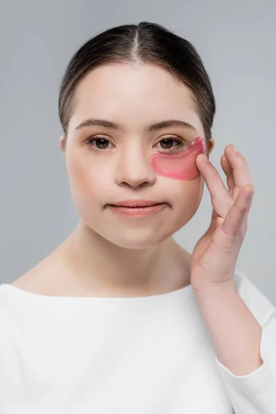 Портрет жінки з синдромом Дауна, що застосовує патч для очей ізольовано на сірому — стокове фото