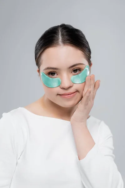 Young woman with down syndrome in blouse applying eye patch isolated on grey — Stock Photo