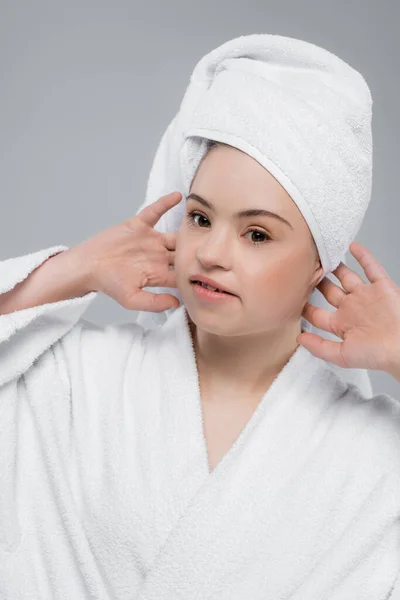 Mulher com síndrome de down em roupão de banho tocando toalha na cabeça isolado em cinza — Fotografia de Stock